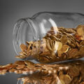 coins spilling from a money jar on gray background